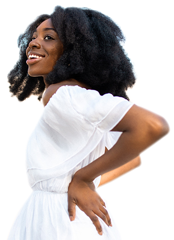 A woman standing in a field with her hands on her hips looking out into the distance and smiling happily.